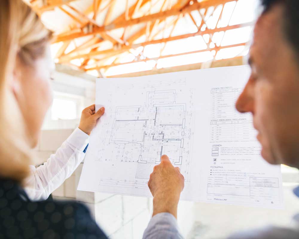 Two architects in a new building being built looking at their design and discussing